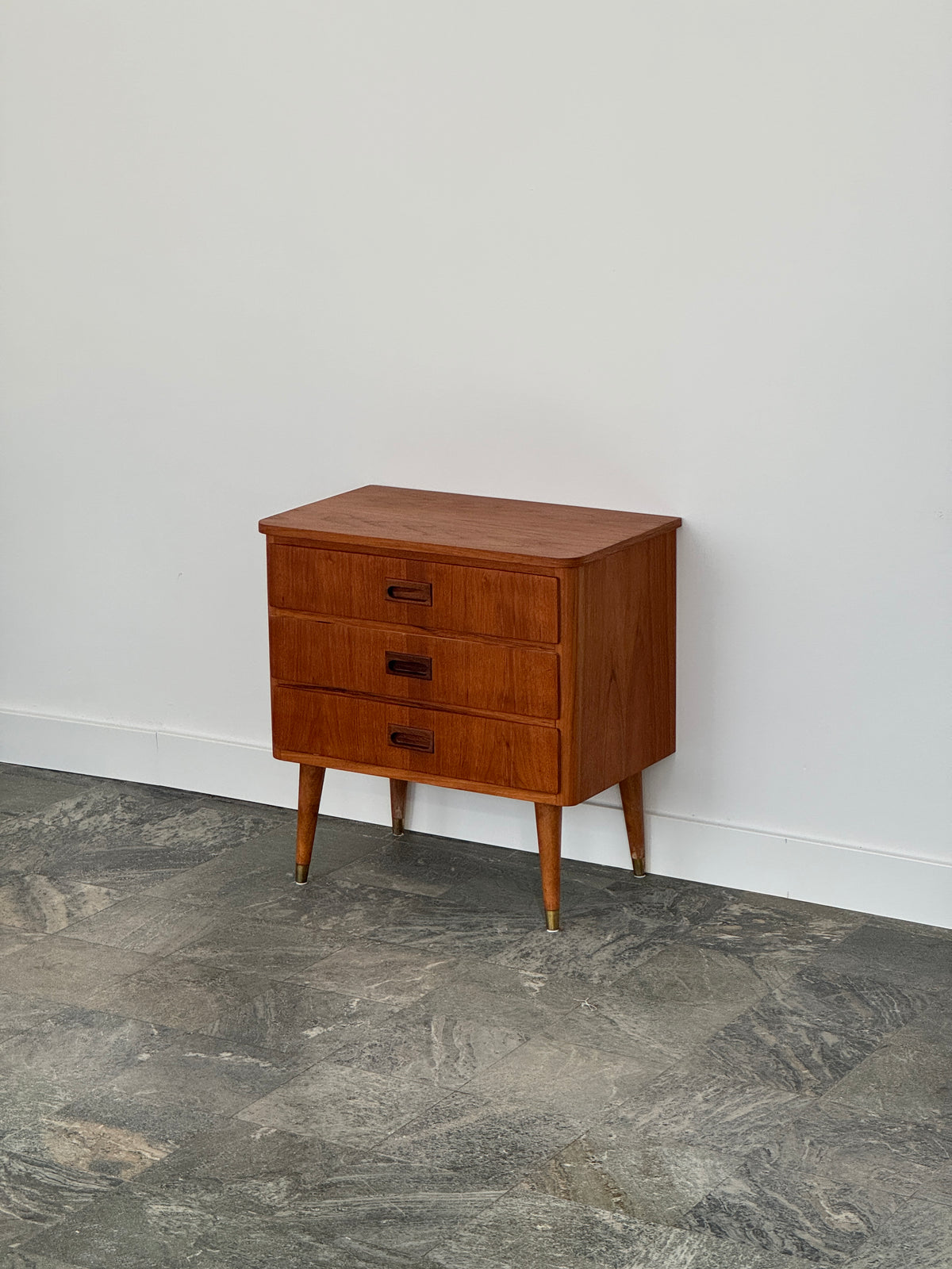 Mindre byrå/sängbord i teak, skålhandtag, tre lådor