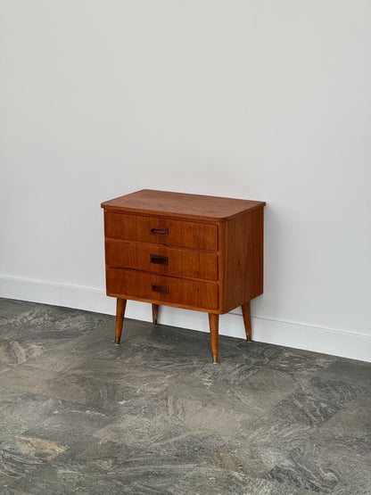 Mindre byrå/sängbord i teak, skålhandtag, tre lådor